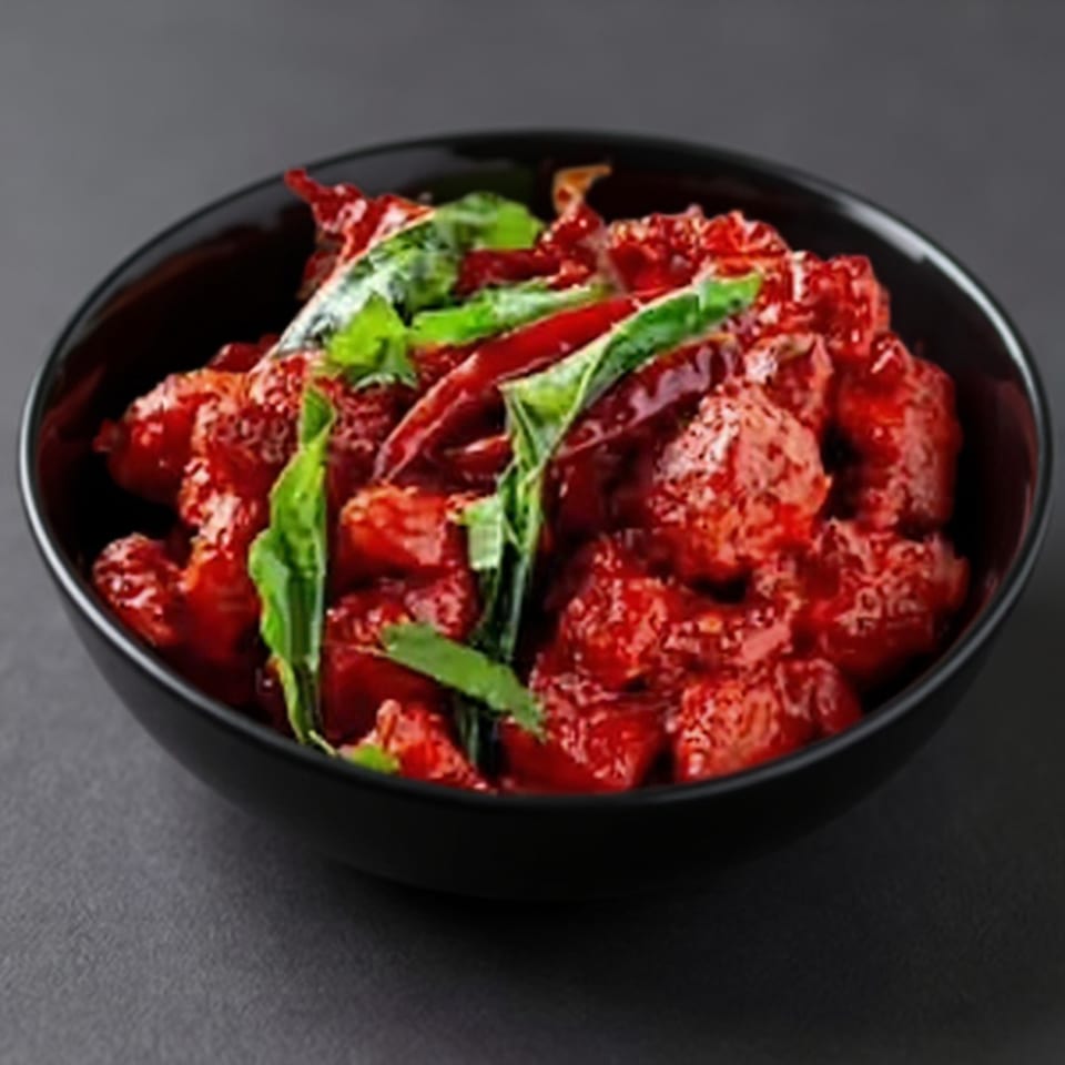 Taj Mahal Grill & Bar's vibrant red Indian chicken dish, garnished with green herbs and red chilies in a black bowl.