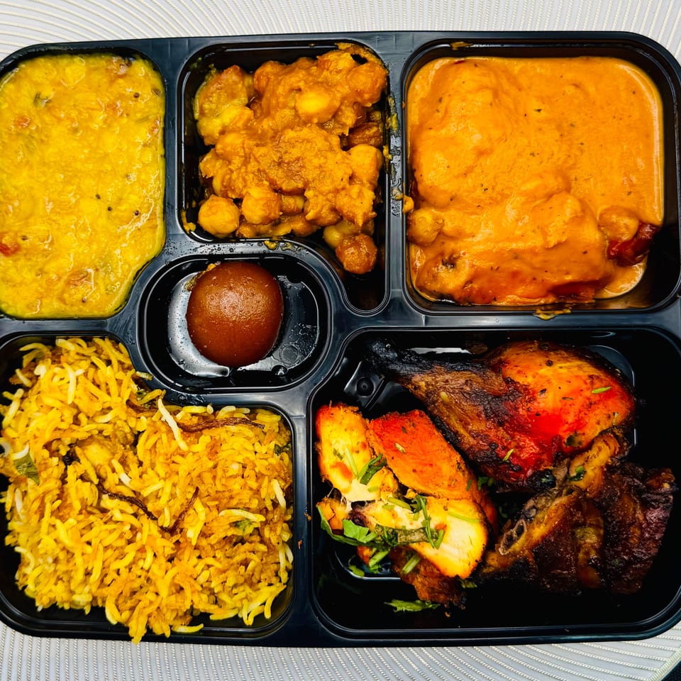 Indian thali with dal, chana masala, butter chicken, biryani, gulab jamun, and tandoori chicken.