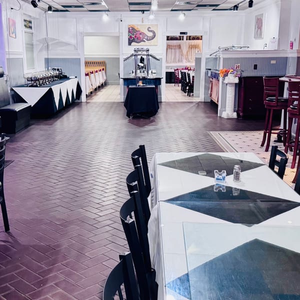 Spacious restaurant interior with black and white tables, buffet stations, and a patterned brick floor.