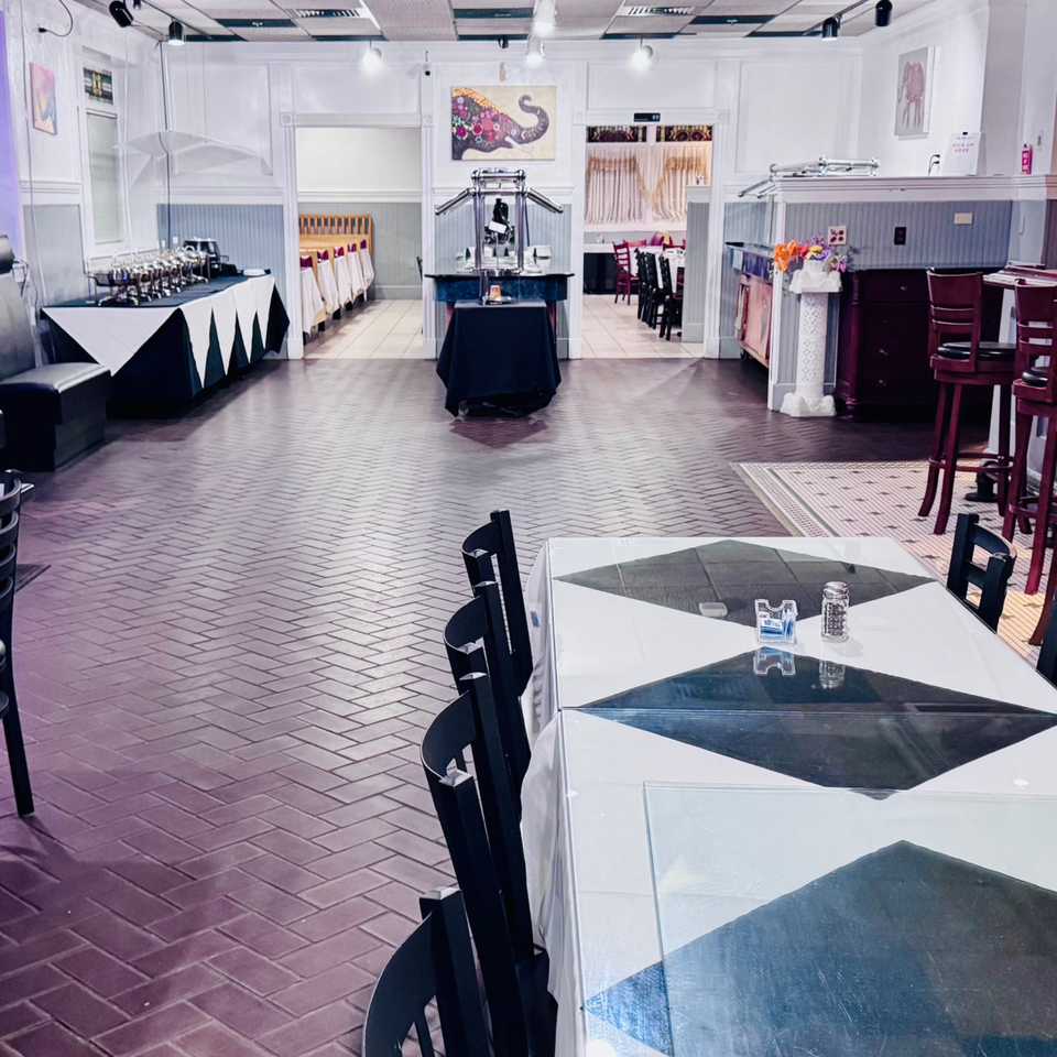 Spacious restaurant interior with black and white tables, buffet stations, and a patterned brick floor.