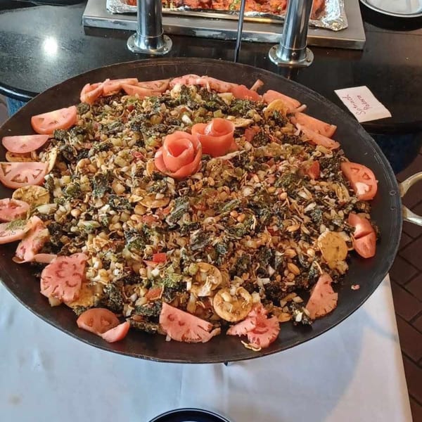 Large pan of Indian spinach pakora, garnished with tomato slices and carved tomato roses.