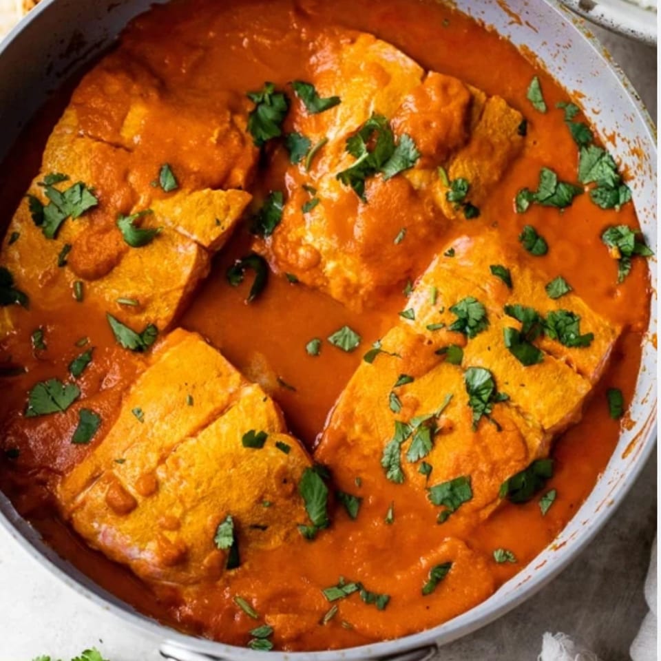Indian paneer butter masala, with large pieces of paneer in a rich orange sauce, garnished with cilantro.